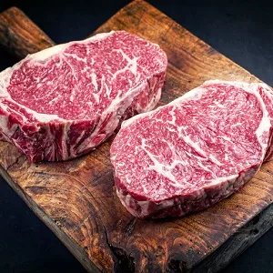 Two raw Wagyu entrecôte steaks on a wooden board